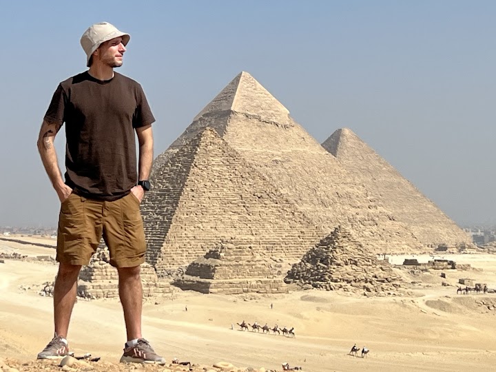 a person standing in front of the pyramids of Giza