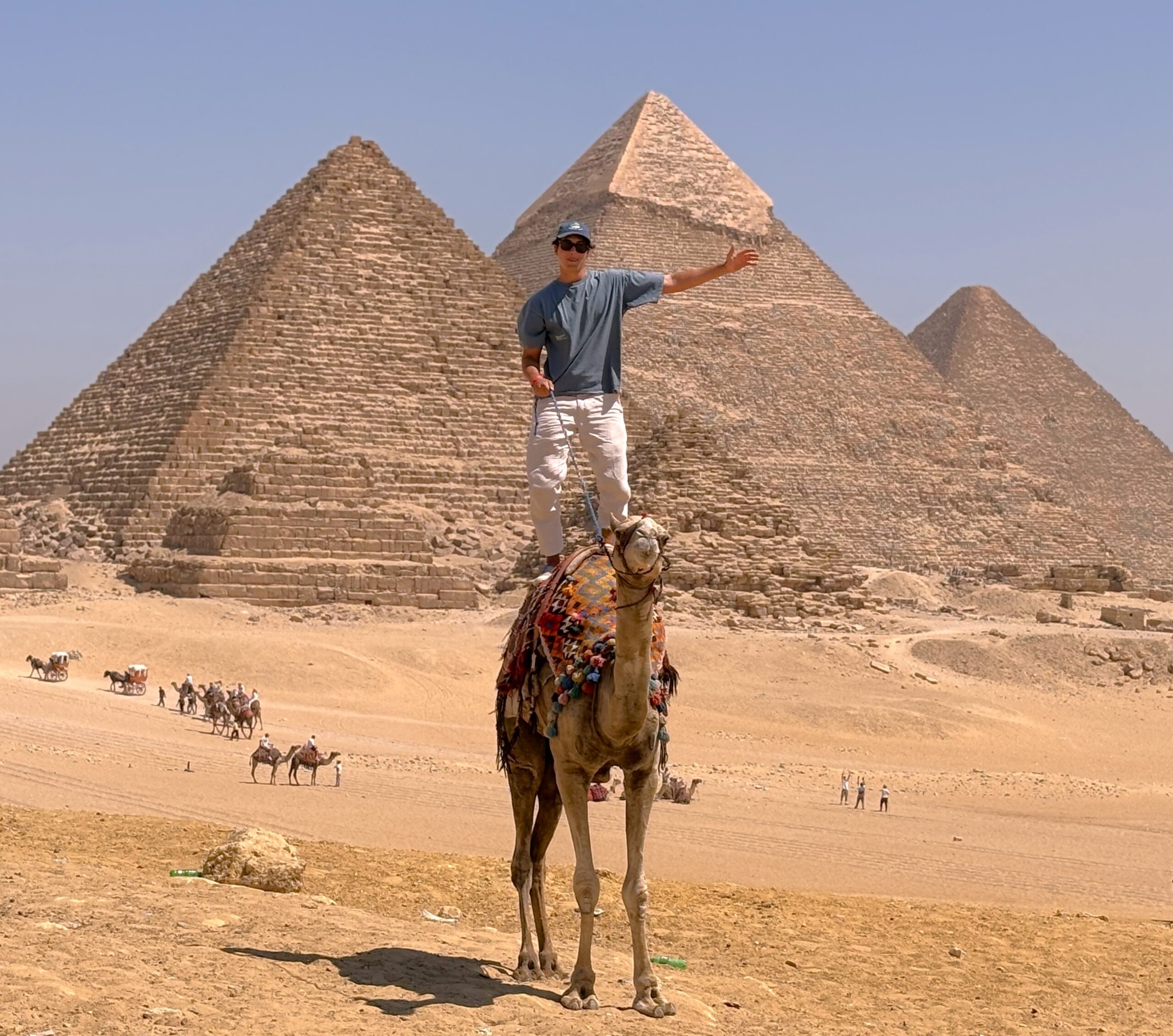 a person standing on a camel in Giza pyramids