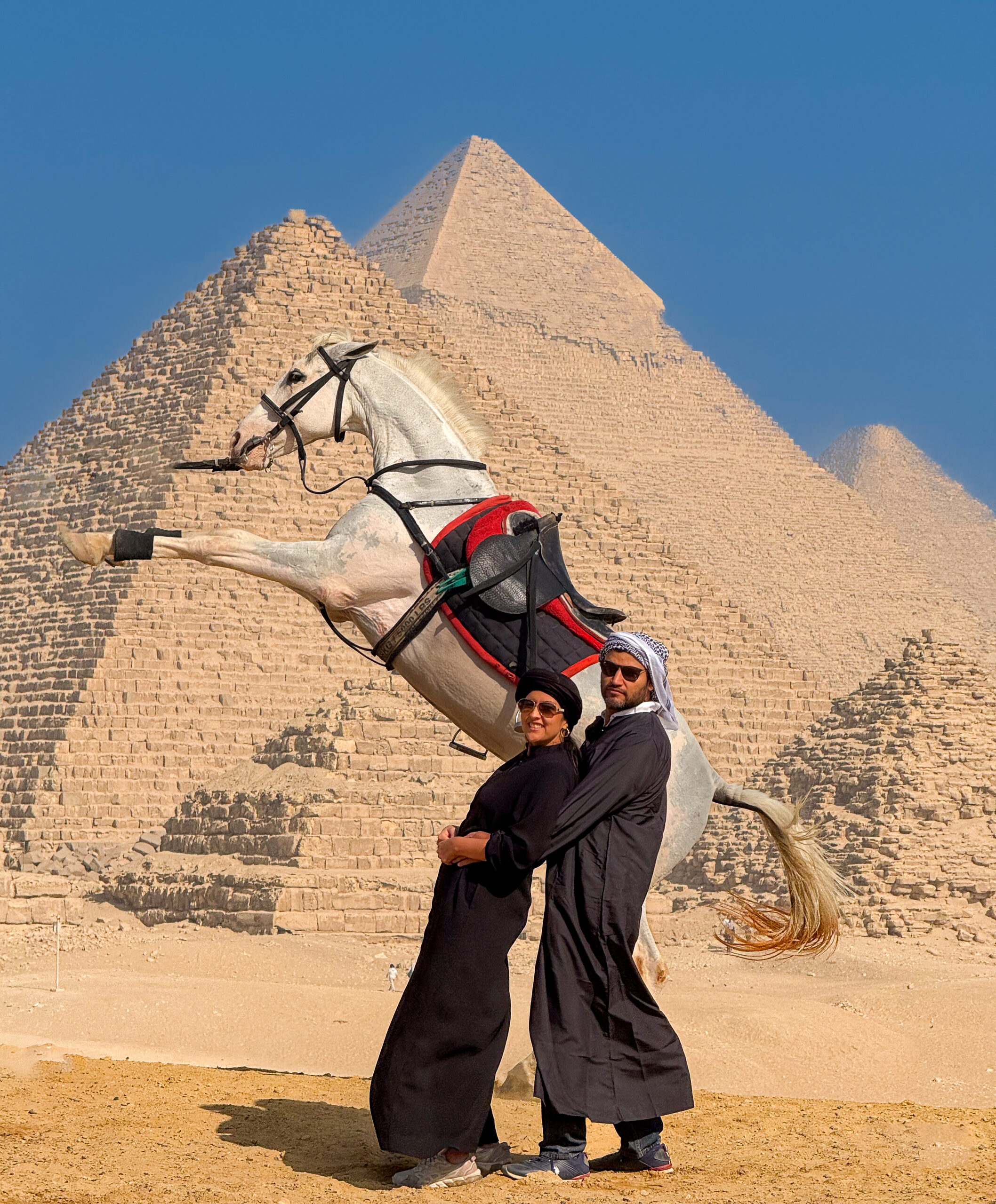 an image of 2 persons standing in front of the pyramids with a horse