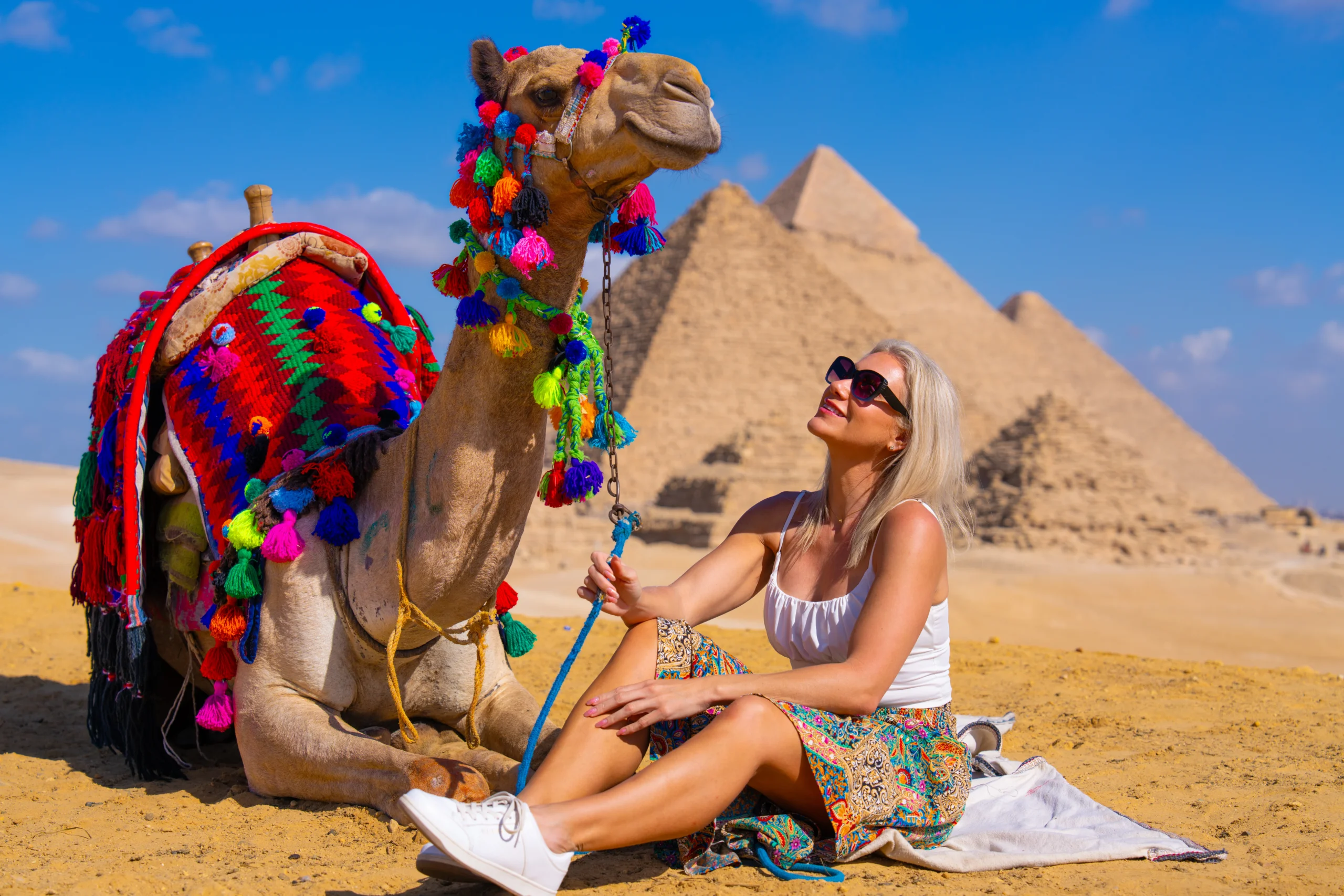Woman posing beside a colorful camel during a Giza Pyramids photoshoot