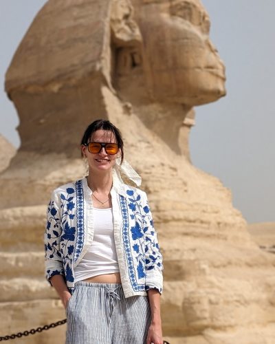 a beautiful girl standing in front of sphinx